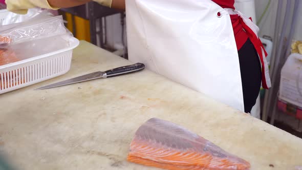 Grocery Store Worker in Gloves Packs Fresh Salmon Fillet In Plastic Portion Bags