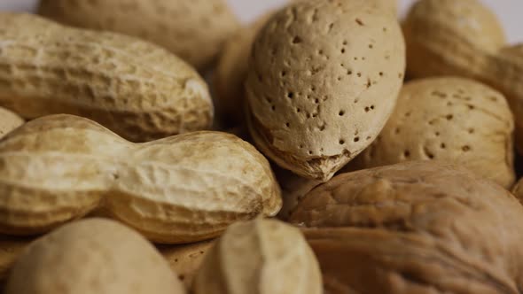 Cinematic, rotating shot of a variety of nuts on a white surface - NUTS MIXED