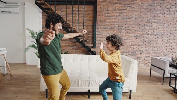 Curlyhaired Siblings Dance Against Sofa in Living Room