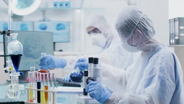 Chemists in Modern and Professional Laboratory Are Looking at Tubes with Colored Liquids alt