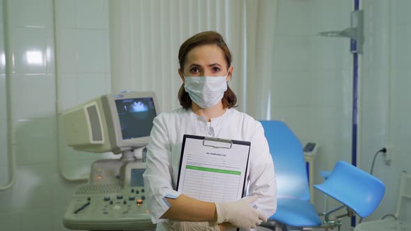 Woman gynecologist with tablet and medical sheet in hands
