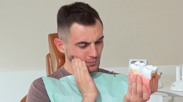 Young Man Having Toothache, Sitting in a Dental Chair at the Clinic