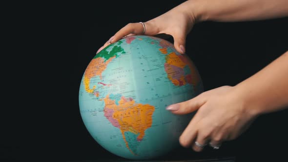 Geographical Globe is Twisted Around Its Axis By a Female Hand