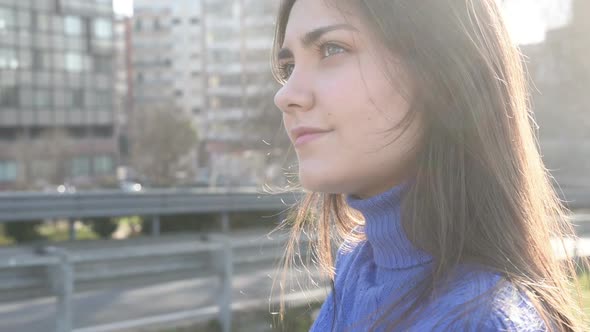 Portrait young woman outdoor back light looking away smiling