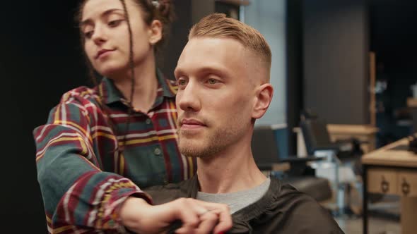 Barbershop: a woman barber shows a haircut to a man client, result of work