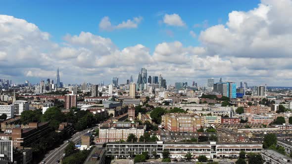 Aerial establishing shot, sliding left to right presenting London skyline against white puffy clouds