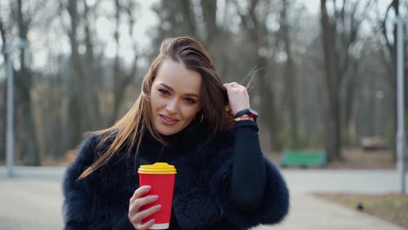 Beautiful woman with a plastic cup outdoors. 