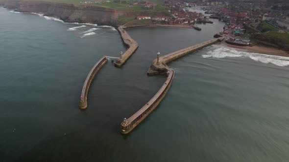 West Pier And East Pier Lighthouse At Whitby Harbour In North Yorkshire, England. Aerial Wide Shot