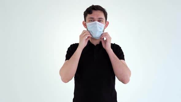 Young Man Wearing Protective Mask Coughs Up in the Fist.