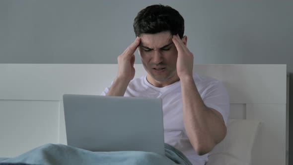 Headache, Tense Young Man Working on Laptop in Bed