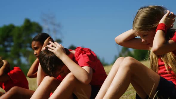 Trainer assisting kids while exercising in the boot camp