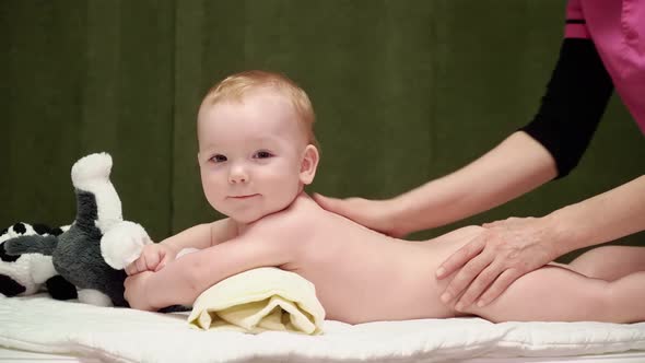 The masseuse gives a back massage to baby (boy) 07