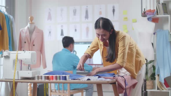 Asian Female Creates A Template Of The Future Dress While A Male Designing Clothes On The Desktop