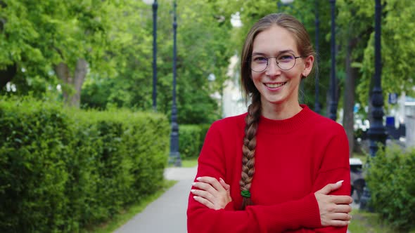 Girl in Red Sweater Smiles at Street Looks to Camera