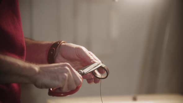 A Man Cuts the Thread After Finishing Sewing the Belt Loop