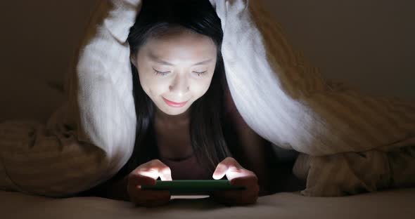 Woman Using Cellphone Under Blanket at Night