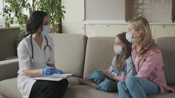 Family Doctor at Patient's Home in Medical Masks Mother with School Daughter Attending Pediatrician