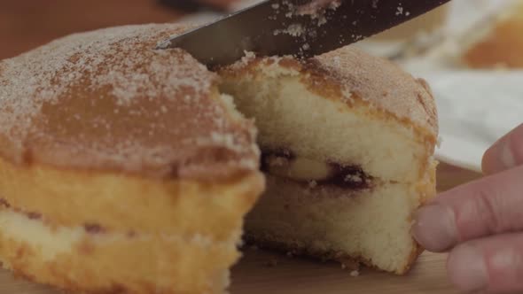 Slicing into a Victoria sponge cake close up shot