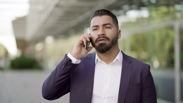 Serious Businessman Talking By Smartphone on Street