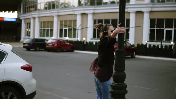 A Beautiful Girl with Sunglasses and Headphones Dancing Circling Around a Lamppost