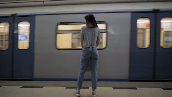 Woman Stands At Underground Metro Station Next To The Passing Train