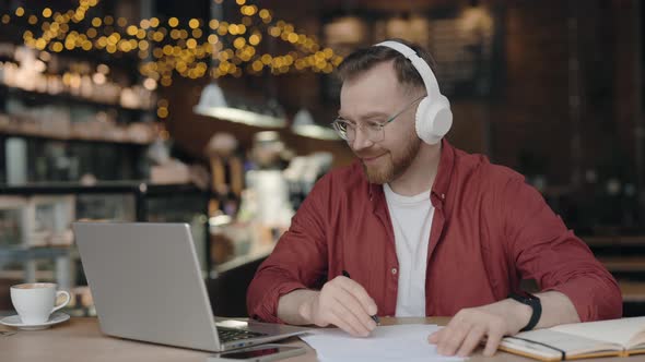 Male Freelancer Sitting at Desk at Cafe and Taking Notes Remotely Studying