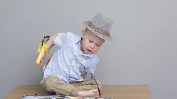 Cute Baby Boy Child Kid in Hat Putting Off School Bag Back to School Concept