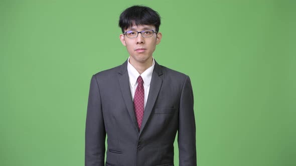 Young Asian Businessman Against Green Background
