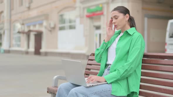 Hispanic Woman with Headache Using Laptop While Sitting Outdoor on Bench