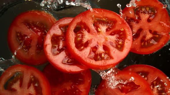 Super Slow Motion Shot of Tomato Slices Falling Into Water on Black Background at 1000Fps