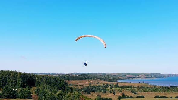 Male Athlete Flying with a Glider in Blue Sky