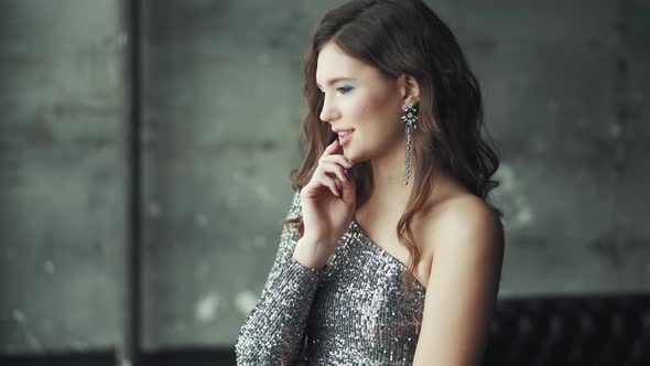 Portrait of Charming and Glamorous Girl in a Beautiful Silver Dress