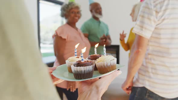 Happy senior diverse people at birthday party with cake at retirement home