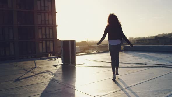 Fashionable young woman on urban rooftop with arms outstretched