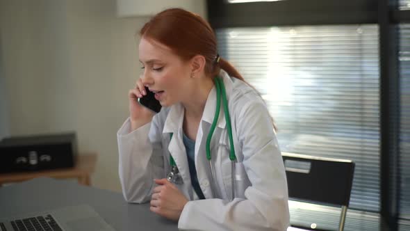 Closeup Face of Cheerful Female Doctor Wearing White Coat Talking on Mobile Phone with Patient