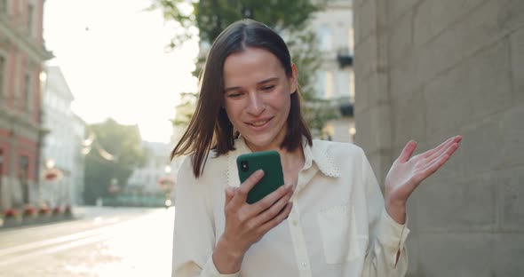 Close Up View of Young Woman Saying Wow and Smiling While Looking at Phone Screen. Cheerful Girl