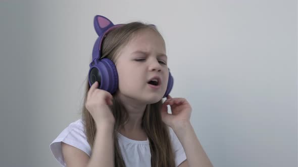 Pretty Caucasian Girl in Big Wireless Headphones with Cat Ears Listening to Music Singing Song and