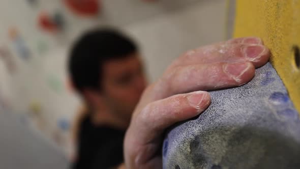 Close-up of a mans hands has he climbs in an indoor climbing gym.