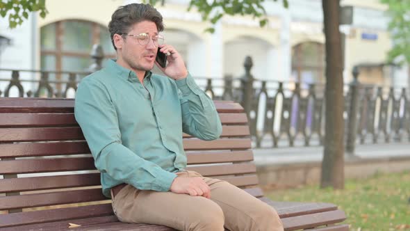 Man Talking on Phone Call while Sitting on Bench