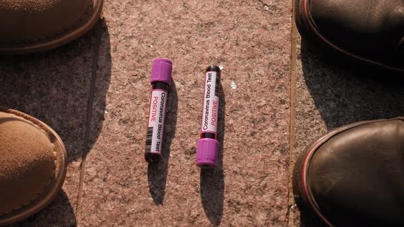 Closeup of Test Tube with a Blood Test for Coronavirus and the Shoes of People