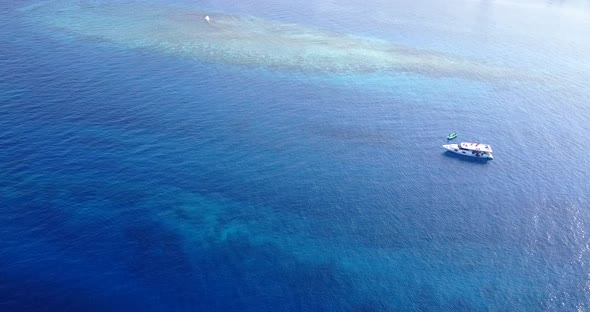 Luxury flying abstract view of a sandy white paradise beach and blue water background in 4K