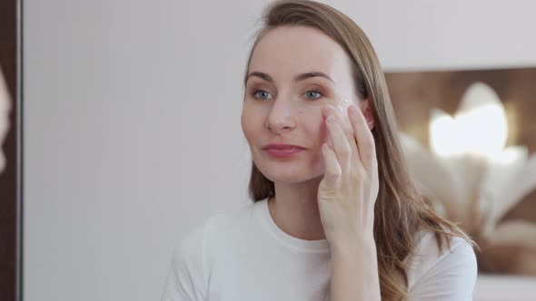 Young Woman Putting Face Cream on Her Nice Healthy Skin