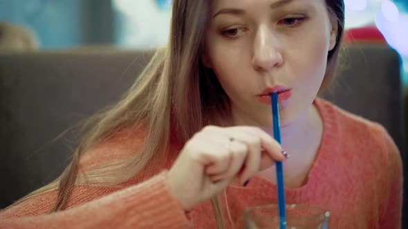 Young Beautiful Girl is Sitting in a Cafe 1