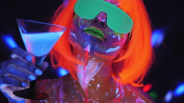 A Girl with an UV Pattern on Her Face in an Orange Wig and Green Glasses Dances