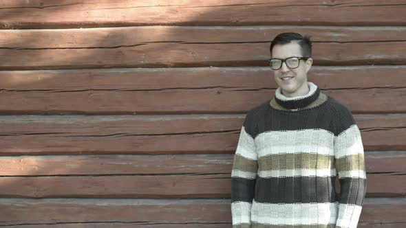 Happy Young Man with Eyeglasses Smiling Against Wooden Wall in Autumn