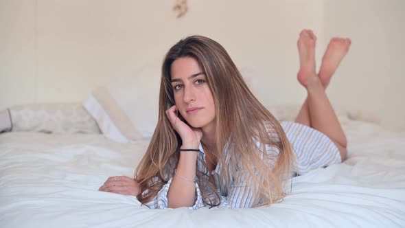 Happy woman lying on her bed looking at camera
