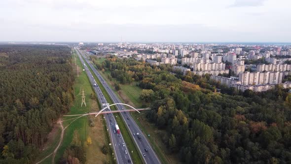 Drone slowly flying towards Kaunas city residential district over the A1 highway with heavy traffic