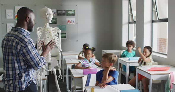 Video of happy african american teacher with class of diverse pupils during anatomy lesson