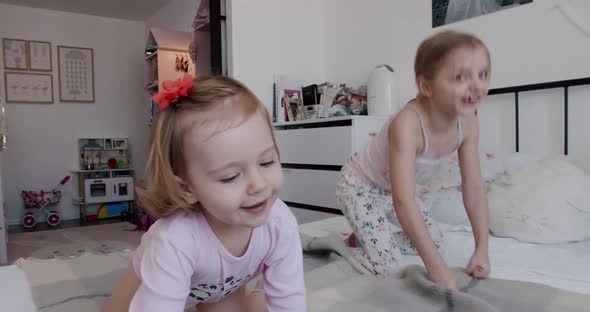 Two Little Girls are Playing at Home Jumping for Joy and Smiling Nicely