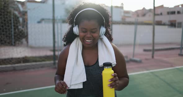 Curvy african woman smiling in camera while doing workout routine outdoor 